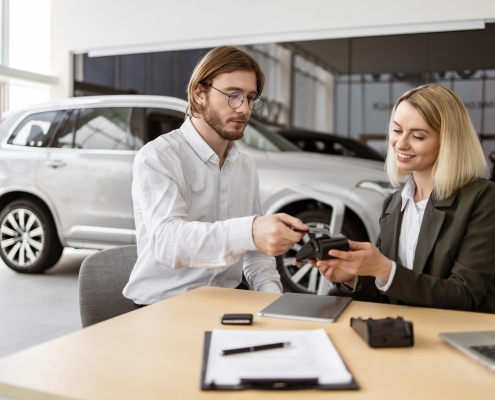 Client et vendeur de voiture remplissant les documents nécessaires à l'obtention d'une carte grise